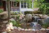 Aquascape® Signature Series™ BioFalls® Waterfall Filter creates a beautiful waterfall in a small garden pond near porch