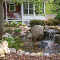 Aquascape® Signature Series™ BioFalls® Waterfall Filter creates a beautiful waterfall in a small garden pond near porch