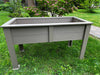 Gray outdoor raised planter box on a grassy area