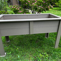 Gray outdoor raised planter box on a grassy area