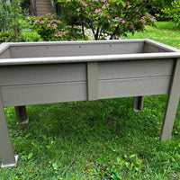 Gray outdoor raised planter box on a grassy area