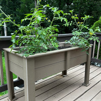 Raised garden poly planter box with plants on a wooden deck