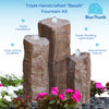 Triple handcrafted basalt fountain rocks with small waterfalls, shown in a garden-style setting with flowers and pebbles. Blue text callouts around the product highlight features like faster installation, easier handling, lightweight design, long-lasting durability, and natural stone texture.