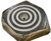 A hexagonal stone basin or fountain feature with concentric circular black and white bands on its polished top surface, set against a plain white background.