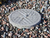 Round stone slab with a circular design on a bed of multicolored stones