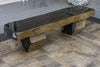 A rustic stone bench made from layered black and gold-brown natural stones, shown on a tiled floor.