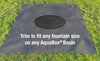 A dark gray rectangular mat laid on green grass, with a circular cutout in the center and white text reading 'Trim to fit any fountain size on any AquaBox® Basin.'.