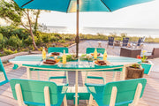 Aruba Blue Surfboard Shaped Table on a Deck with Chairs Surrounding it on the beach with umbrella