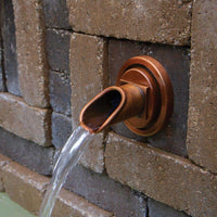 Atlantic Water Gardens Copper Finish Ravenna Wall Spout set within patio hardscape