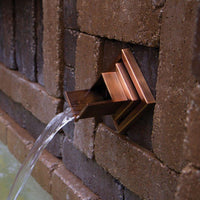 Atlantic Water Gardens Copper Finish Verona Wall Spout set within patio hardscape